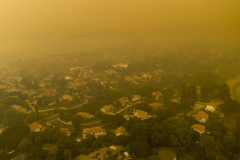 Aerial shot of a town and neighborhood covered in smoke from a fire, air pollution and hazardous air quality. 